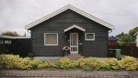 Gable of a small dark-grey wooden house.