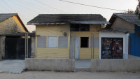 Facade of a small cream-colour wooden house.